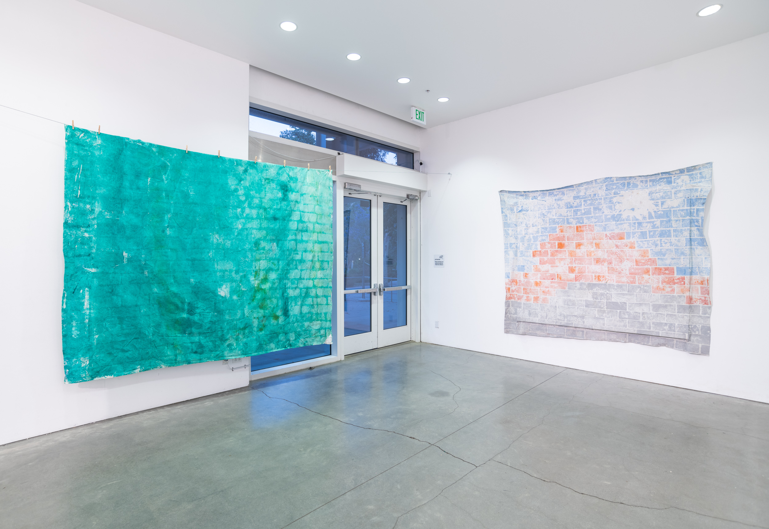 Installation views thesis exhibition containing colorful paintings stretched and unstretched, hanging in space and attached to the wall
