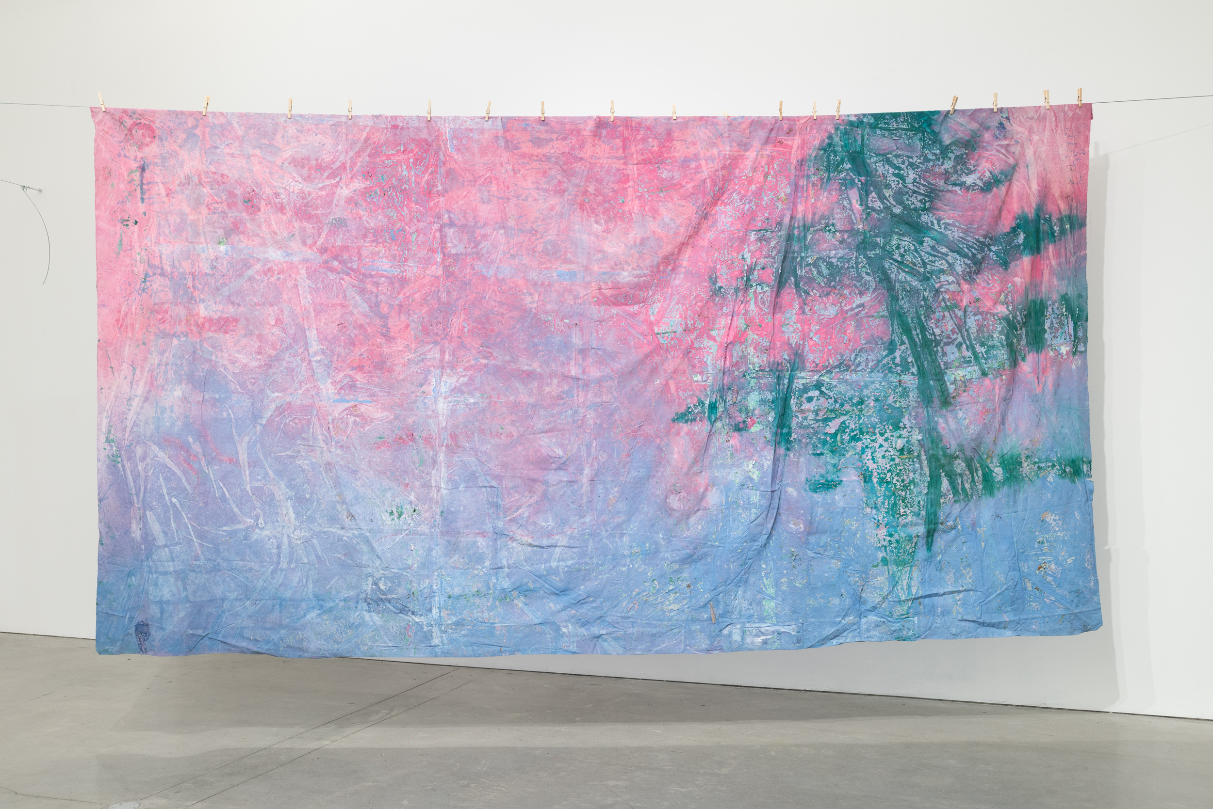 Pink and green hanging fabric attached to steel wire with wooden clips
