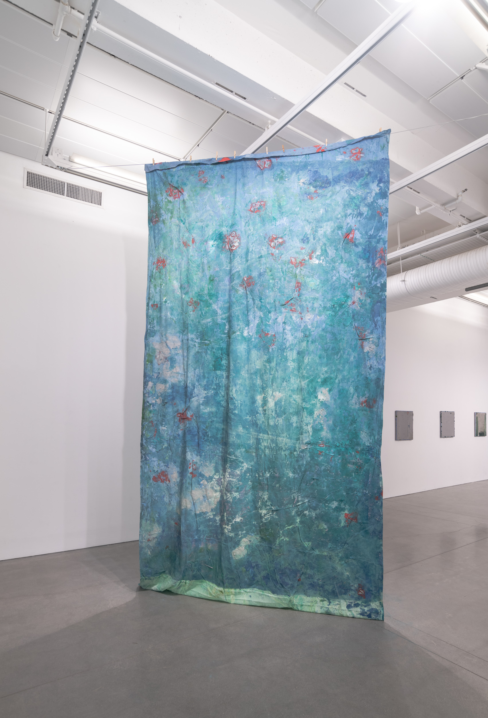 Installation views thesis exhibition containing colorful paintings stretched and unstretched, hanging in space and attached to the wall
