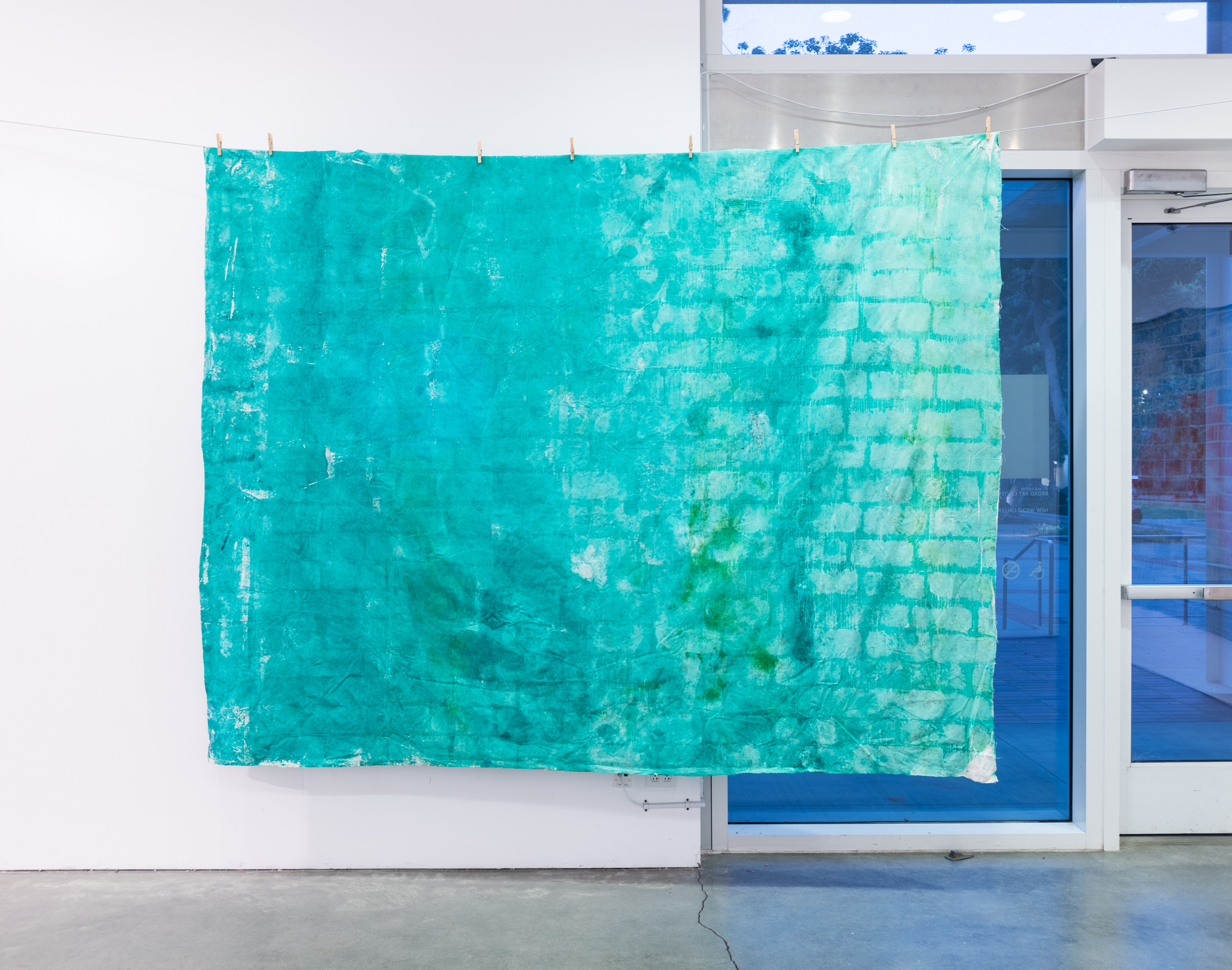 Installation views thesis exhibition containing colorful paintings stretched and unstretched, hanging in space and attached to the wall
