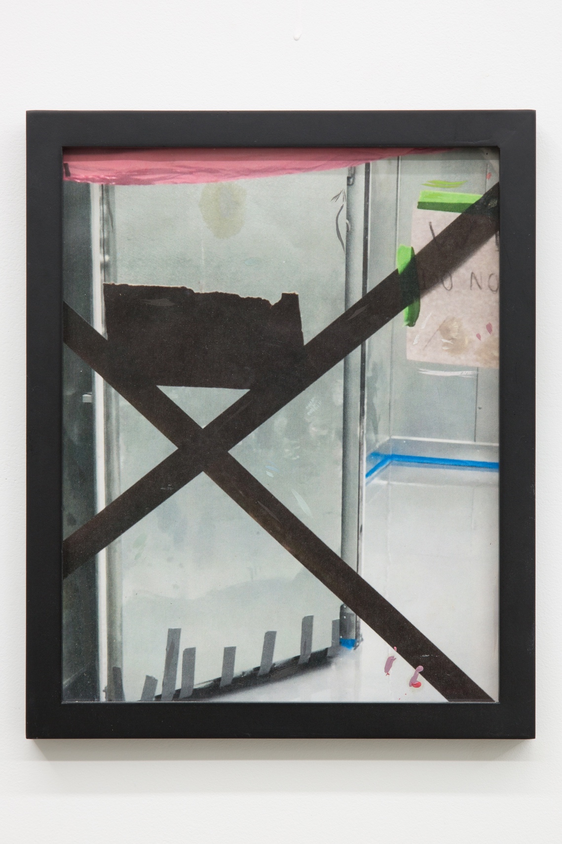 Detail image of a printed photograph framed in a thin matte black frame. The printed image has small marks of oil paint. The image is of two pieces of tape, backlit, and blocking entry to an under-construction industrial sized walk-in freezer.