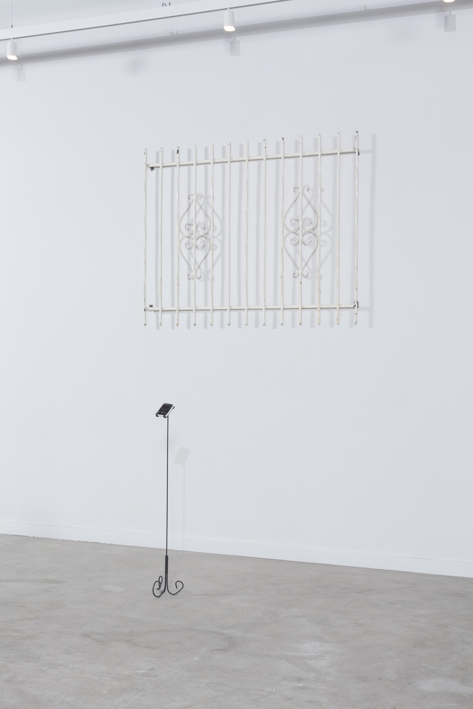 Installation image of one of the ornate metal grates and a baby monitor stand.
