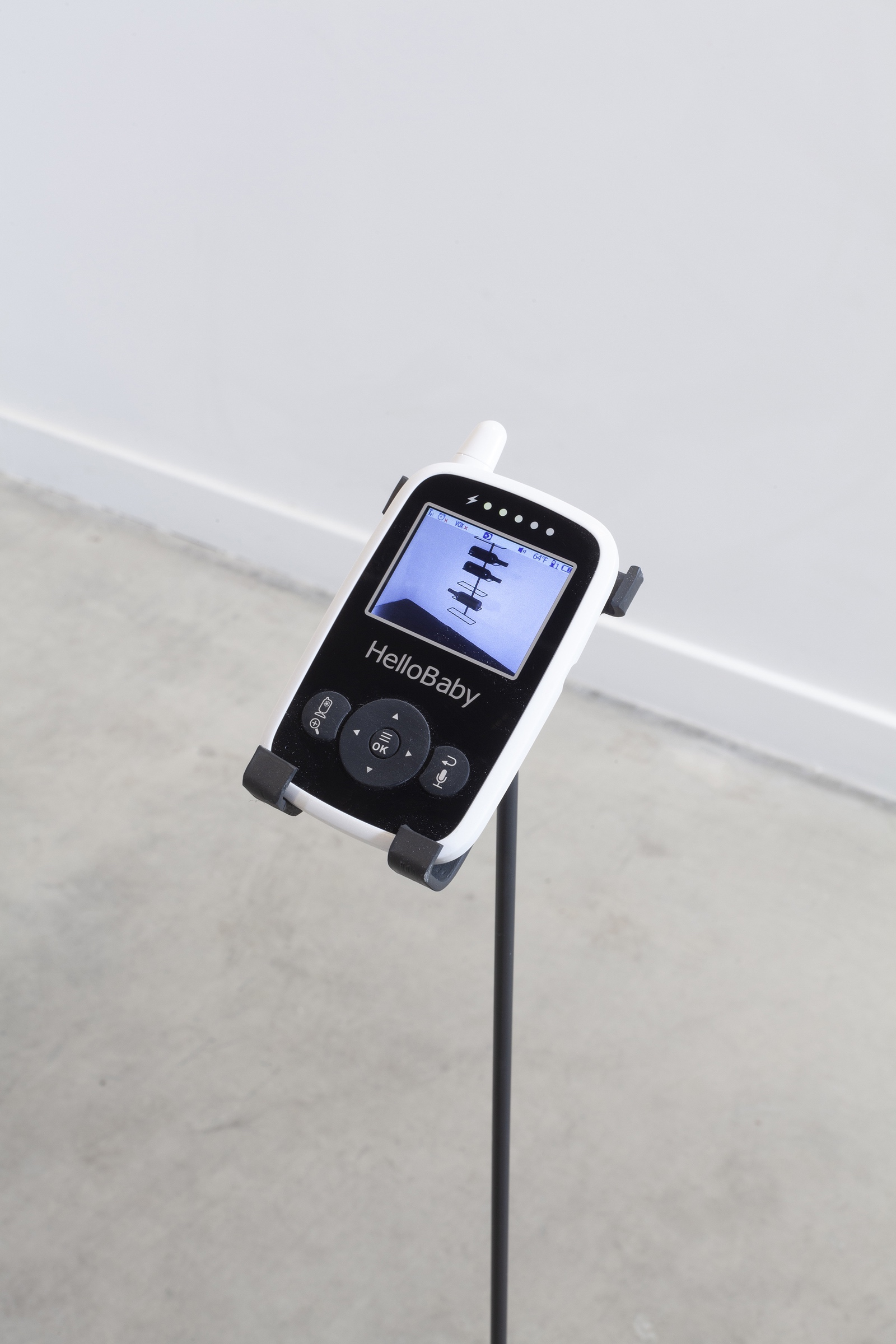 Detail image of one of the faces of the baby monitor. It provides live surveillance of three bottles of palm wine resting on a metal wine rack