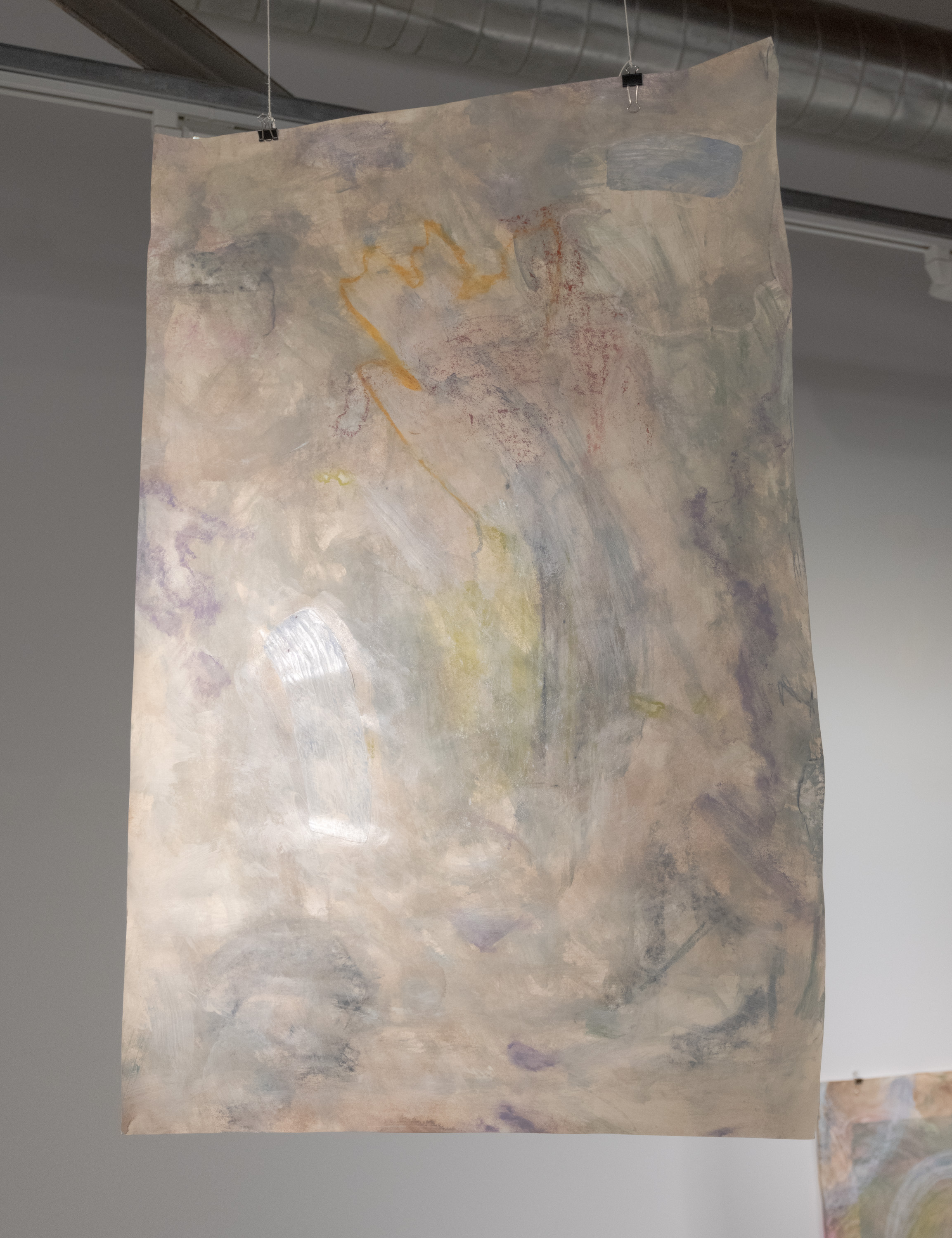 Sheet of paper with washes of walnut ink and gray-green acrylic paint is suspended from the ceiling. Strokes are visible and apparent. The negative spaces from these strokes are outlined by various colors but they are muddled and fade into the background. Various small mylar pieces reflect light.
