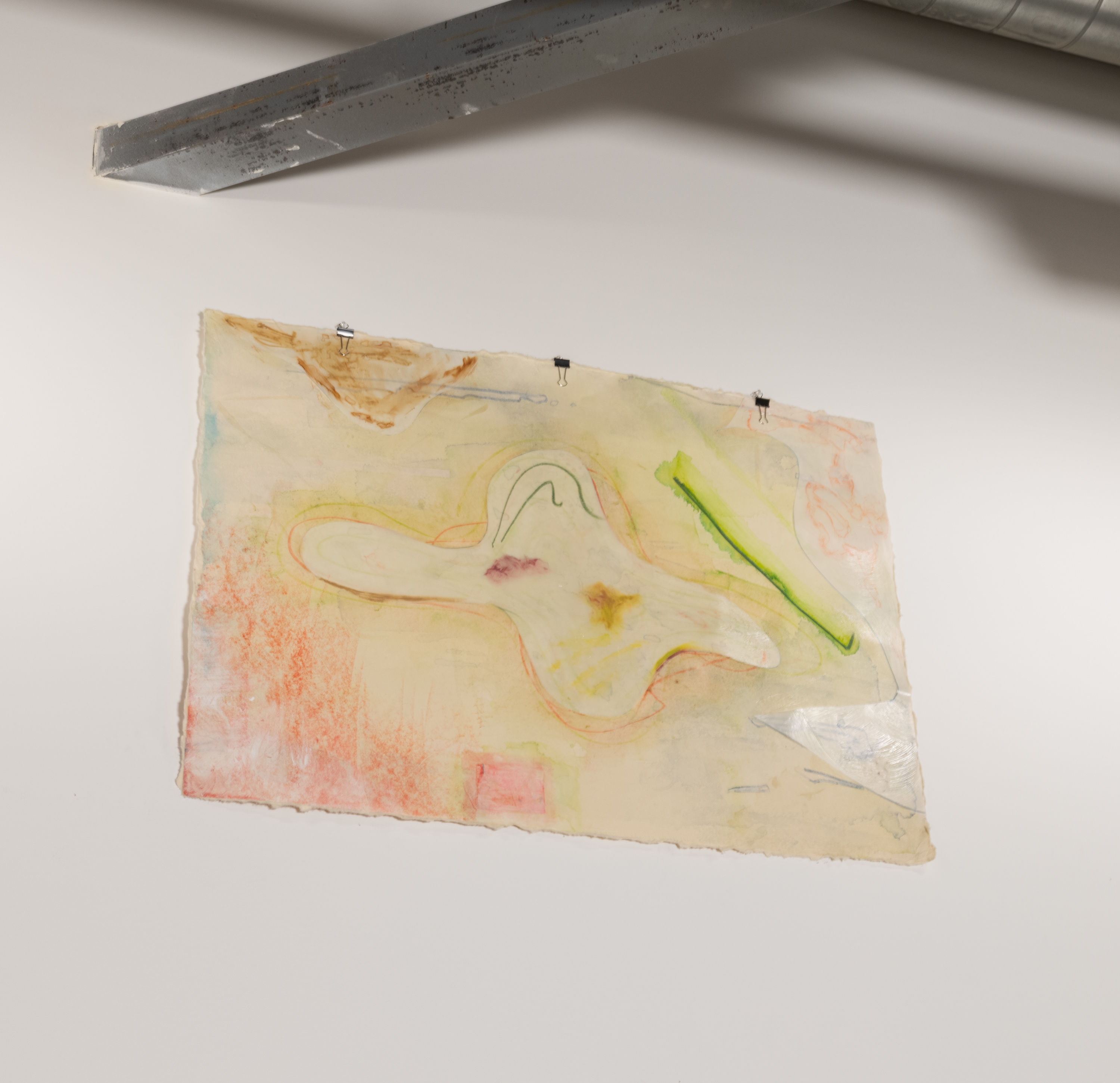 This work sits close to the ceiling and is easy to miss. An abstract collaged piece of mylar resembling an amoeba sits in the center of the paper. The background is washed out with muddled blues, greens, pinks, and yellows. Various collaged mylar pieces occupy the top left and right hand side. The mylar pieces possess a slight sheen from the light and have pale hues of brown, pink, and blue. The bottom left has large red oil pastel strokes shooting from the bottom.