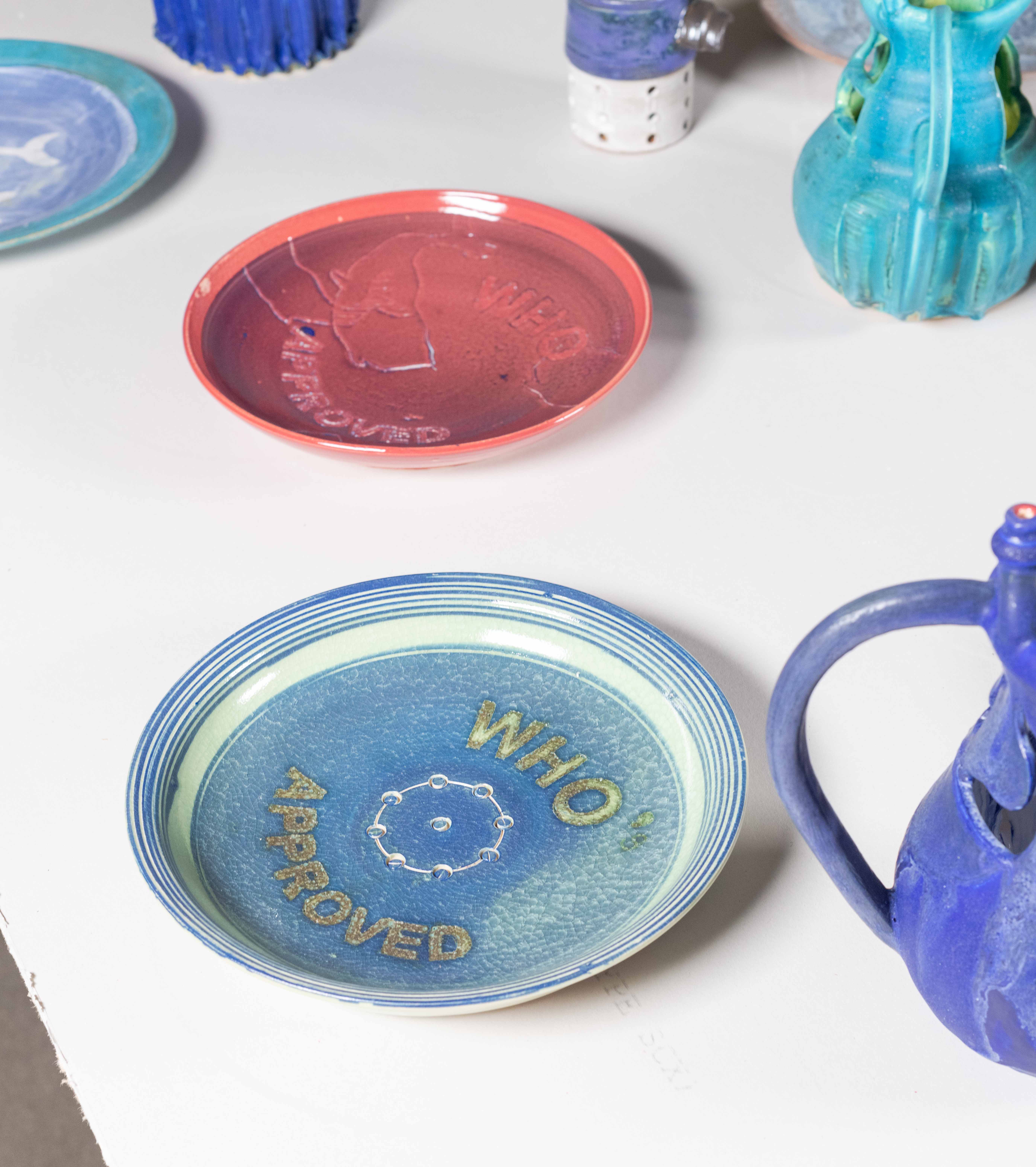 Drywall table with LED lights imbedded below the surface. 25 pound iron weights for
lifting are the tables wheels. The table legs are an outline of a horses feet. On top of the table
are an assorted gathering of brightly glazed Ceramic objects— Puzzle Jugs and WHO plates.