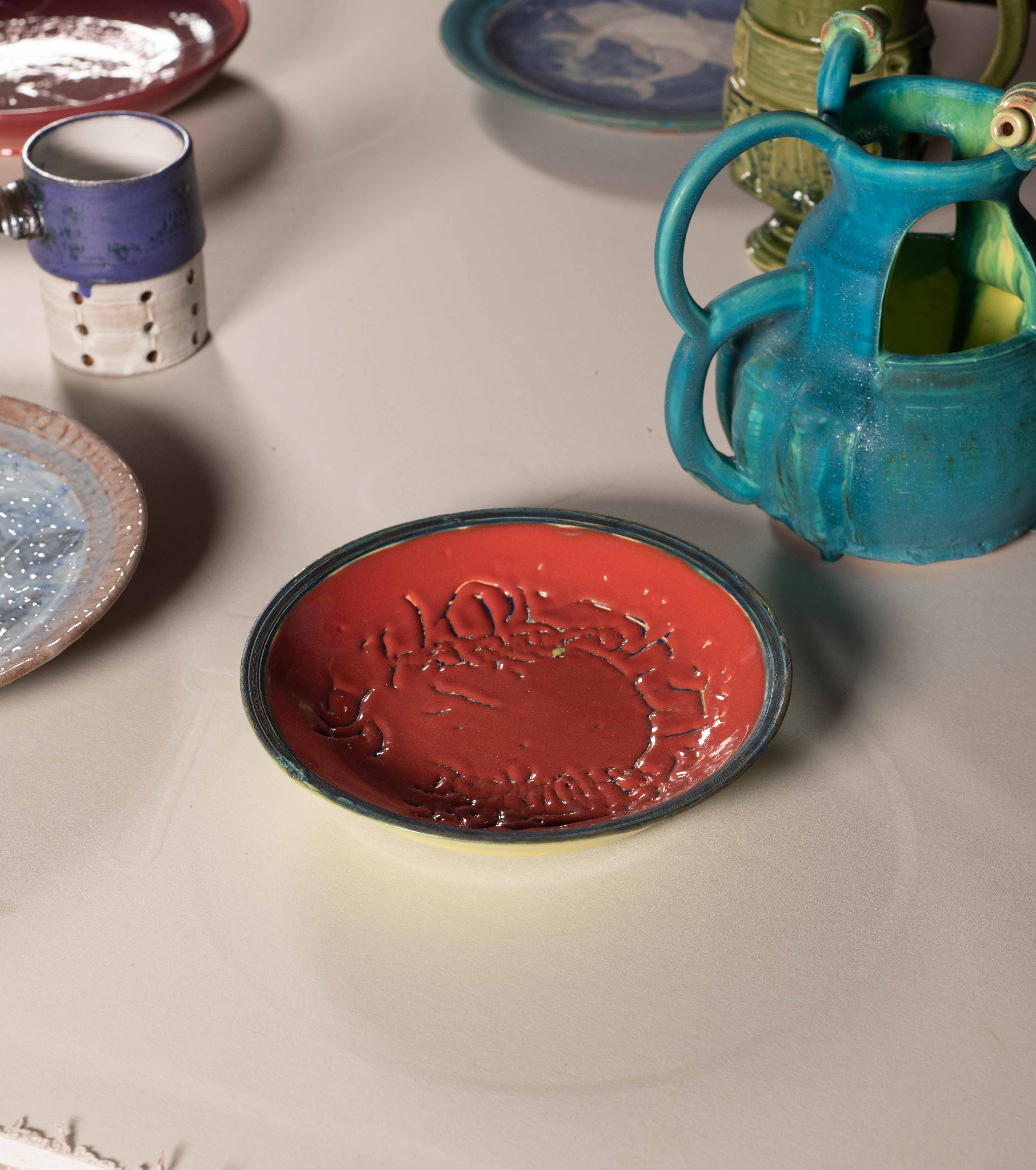 Drywall table with LED lights imbedded below the surface. 25 pound iron weights for
lifting are the tables wheels. The table legs are an outline of a horses feet. On top of the table
are an assorted gathering of brightly glazed Ceramic objects— Puzzle Jugs and WHO plates.