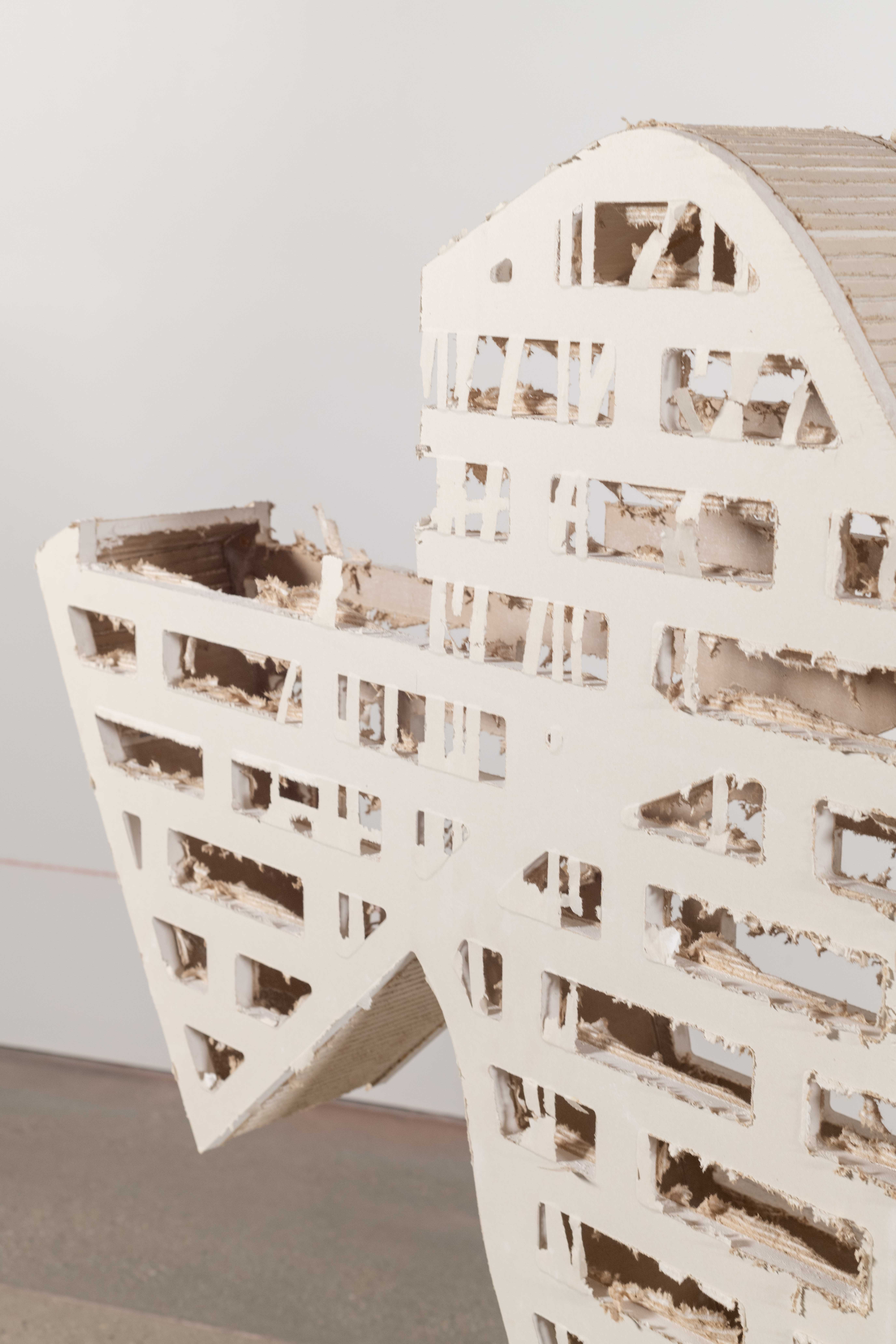 Drywall cut in the shape of the silhouette of a trojan Horse. The head, piece of the
tail, and legs have been removed, A brick pattern is cut into the interior of the horse. You can
look at the stratification that builds the form. From the paper on the outside of the drywall, to
the interior gypsum and brown paper oN the back of the substrate.